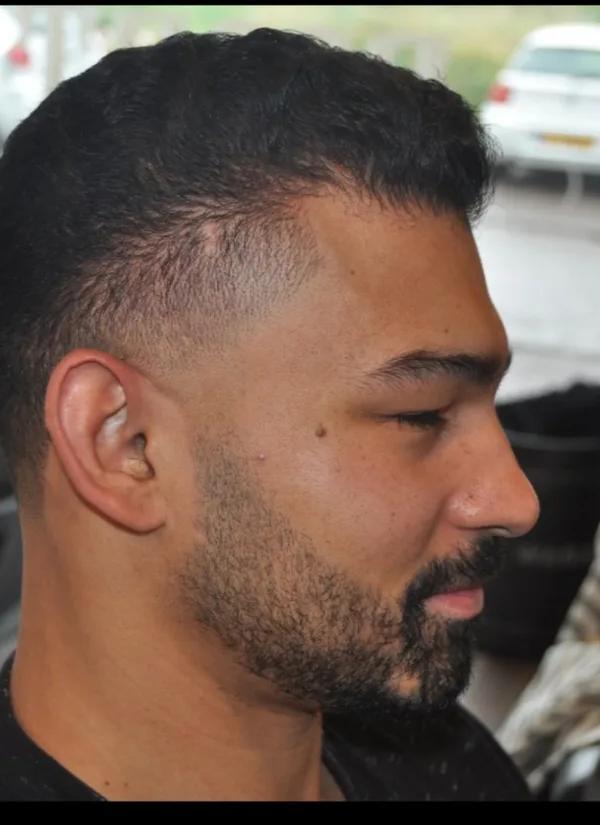 Strakke fade kapsel met baard contour, zijaanzicht in barbershop