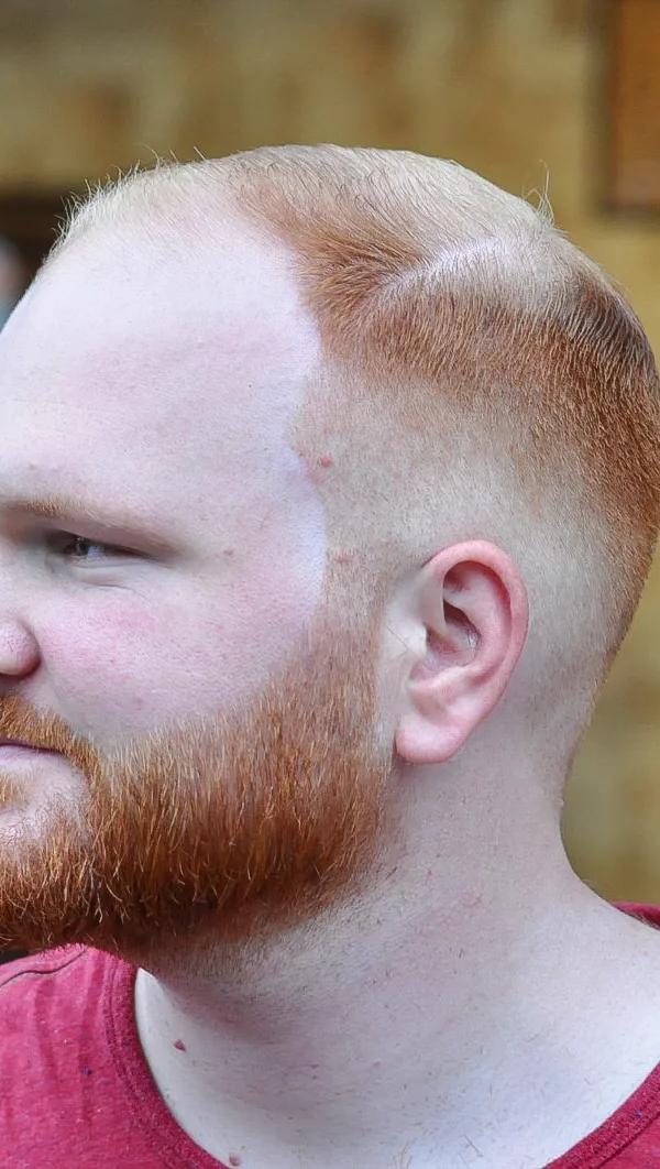 Skin fade met volle rode baard en strakke contour, profielportret