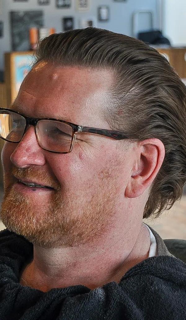 Slick back kapsel met bril en rode baard, klant in barberstoel