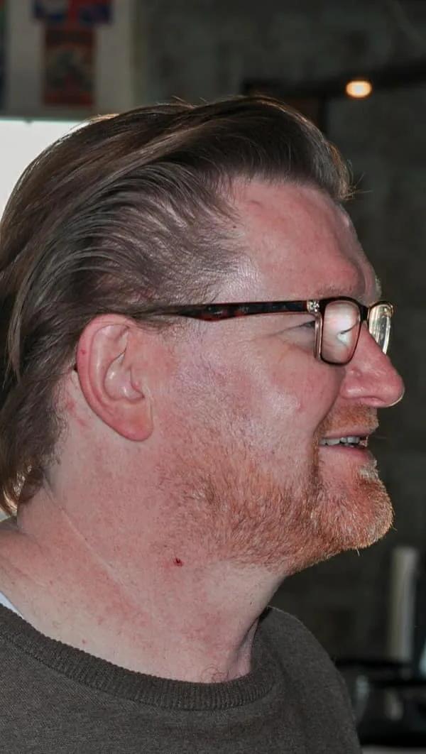 Lange slick back kapsel met baard en bril, profielportret