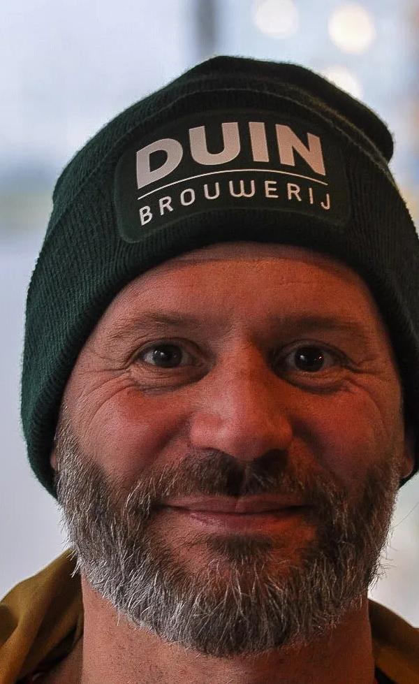 Frontaal portret van klant met grijze baard en beanie na knipbeurt