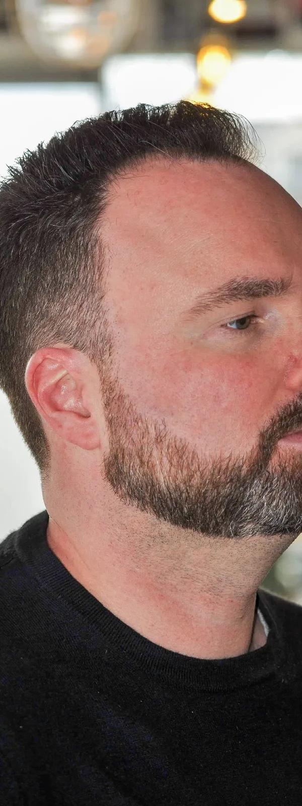 Korte fade met getrimde baard met grijze accenten, profielportret