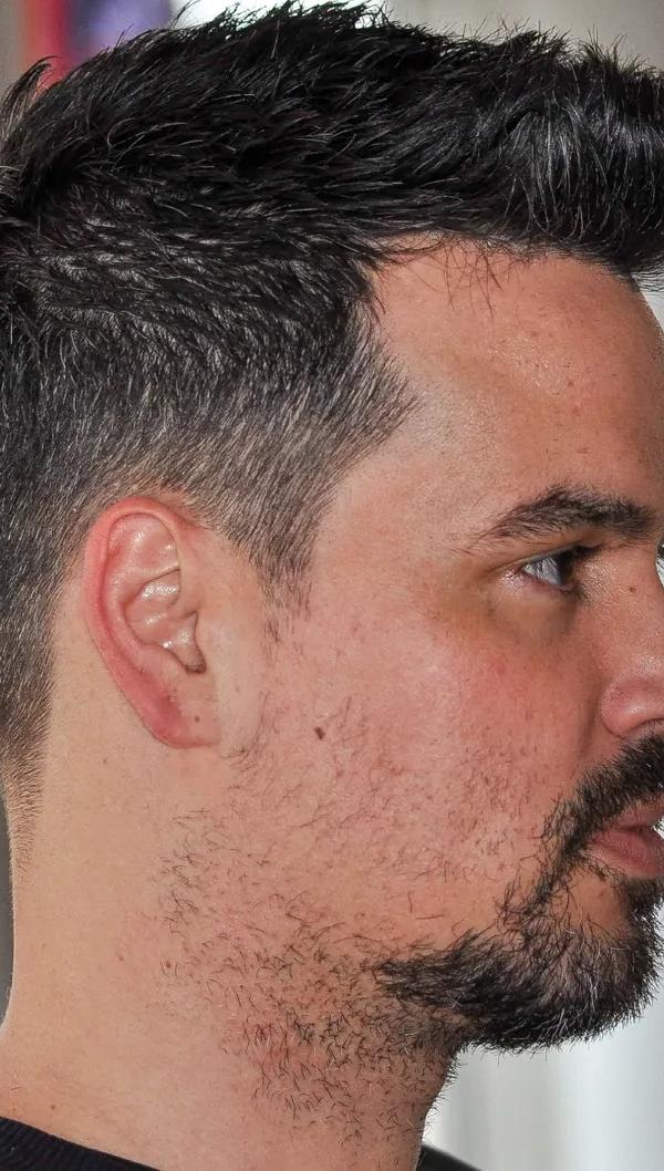 Textured quiff met taper fade en getrimde baard, profielportret