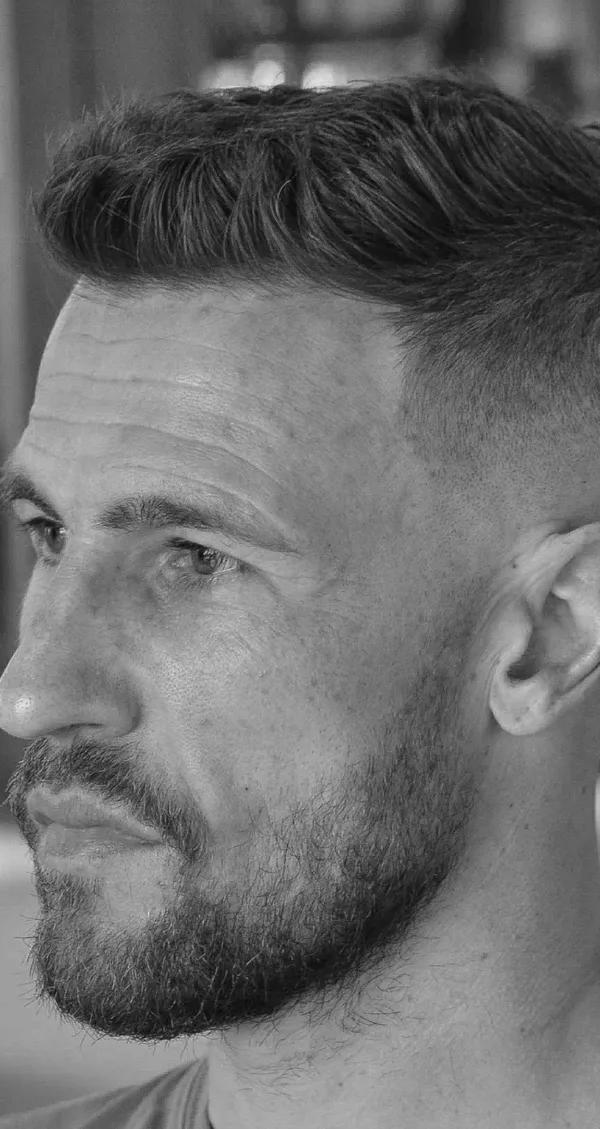 Klassieke pompadour met skin fade en baard, zwart-wit profielportret