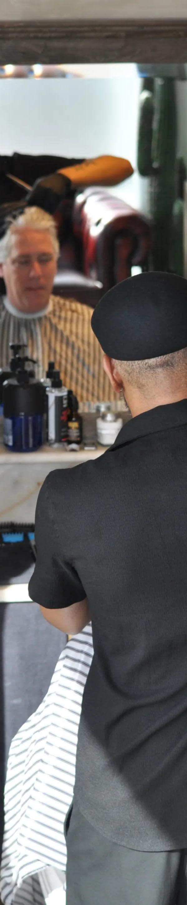 Barber knipt klant — zicht via spiegel in Barber Poort Almere Poort