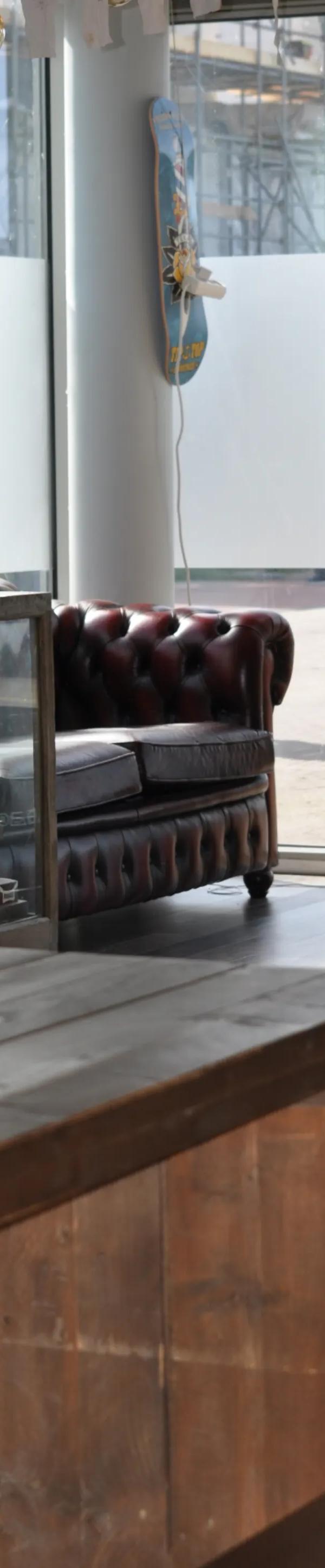 Chesterfield-bank en vitrine bij raam — Barber Poort Almere Poort